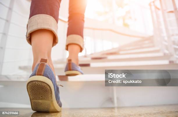 Young Adult Woman Walking Up The Stairs With Sun Sport Background Stock Photo - Download Image Now