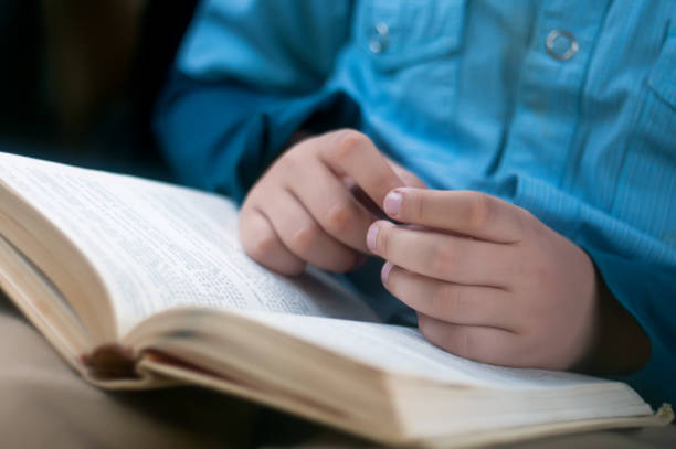 istock Child's hands are on the open book 874250626