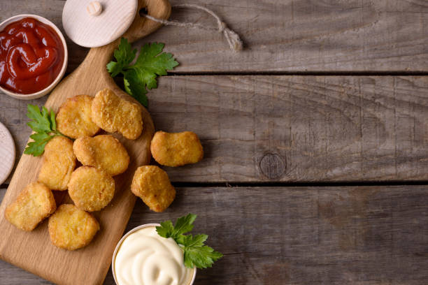 istock Chicken nuggets and sauces on wooden background 874257562