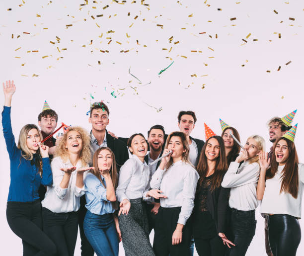 istock Happy smiling young people with gift boxes and blowing party whistles. 874258430