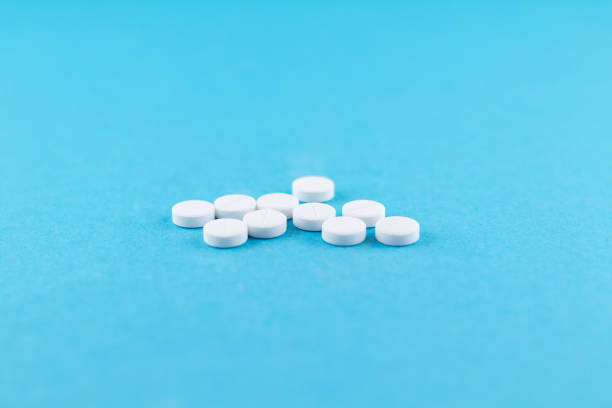 istock White pills with copy space on blue background. Focus on foreground, soft bokeh 874276982