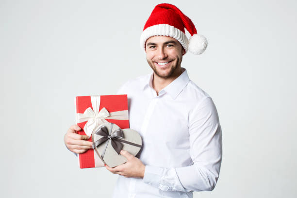 istock Attractive smiling man in Santa hat with gift boxes. 874279200