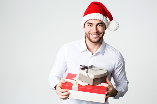 Smiling man in Santa hat with gift boxes. Concept Christmas, holiday, new year.