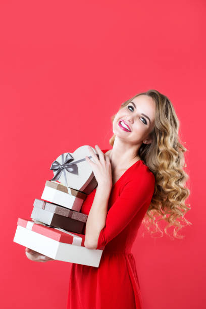 istock Smiling woman in a red dress with many gift boxes. 874282112