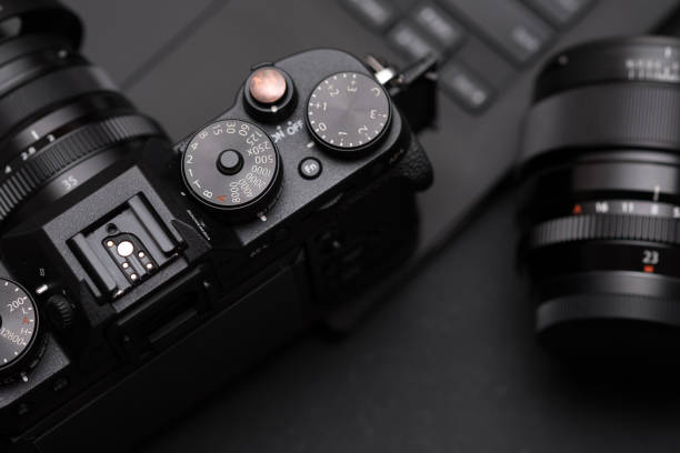 digital mirrorless camera, lens and laptop on desk. concept of photographer work space - color intensity fotos imagens e fotografias de stock