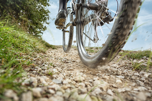 Back wheel of a bicycle in motion on a gravel road.