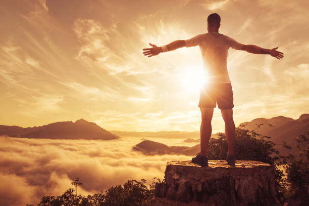 istock Man on a mountain top above the clouds 874294908