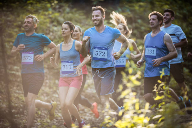 istock Athletic people running a marathon race through the forest. 874298240