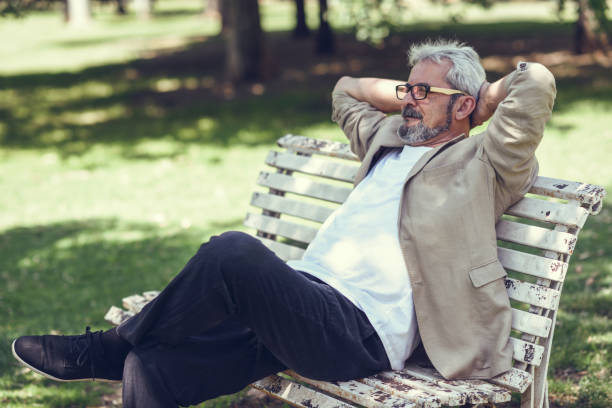 istock Pensive mature man sitting on bench in an urban park. 874298340