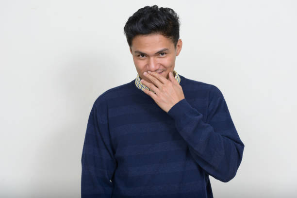 istock Young Asian man wearing purple sweater against white background 874301830