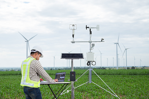 Engineer using tablet computer collect data with meteorological instrument to measure the wind speed, temperature and humidity and solar cell system on corn field background, Smart agriculture technology concept