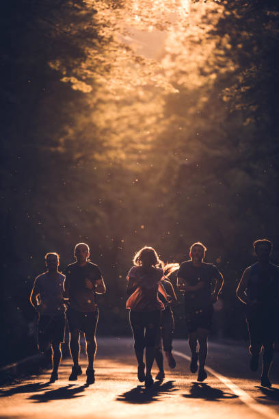 istock Group of determined athletes running a marathon at sunset. 874304778