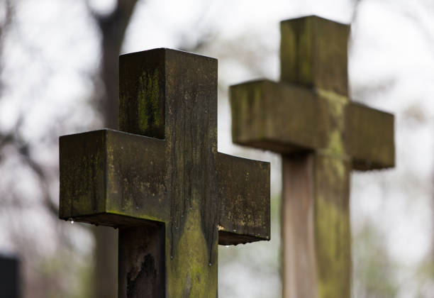 istock Stone cross in cemetery in November rain. 874313296