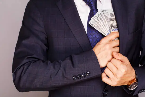 Photo of Businessman putting money in suit jacket pocket