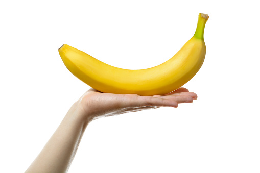 Woman's hand holding ripe banana. Isolated