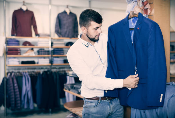 istock Handsome adult guy  choosing modern jacket in men store 874327258
