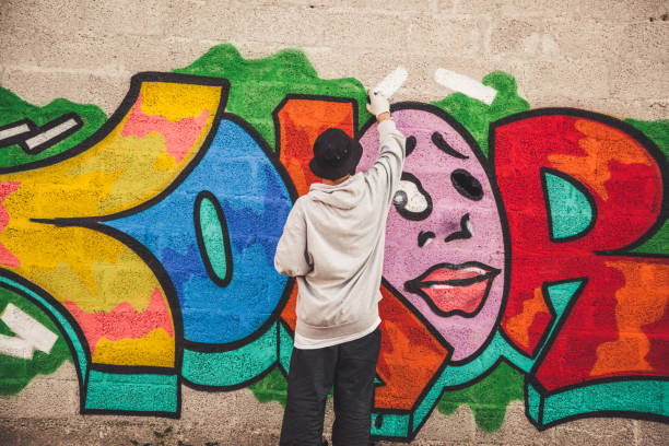 istock Graffiti Artist Spraying Paint on the Wall 874327940