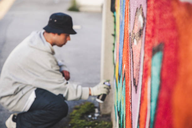 istock Kneeling Graffiti Artist Spraying the Wall 874327978