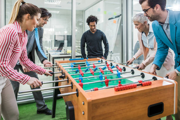 istock Playful business people having fun while playing foosball on a break in the office. 874330932