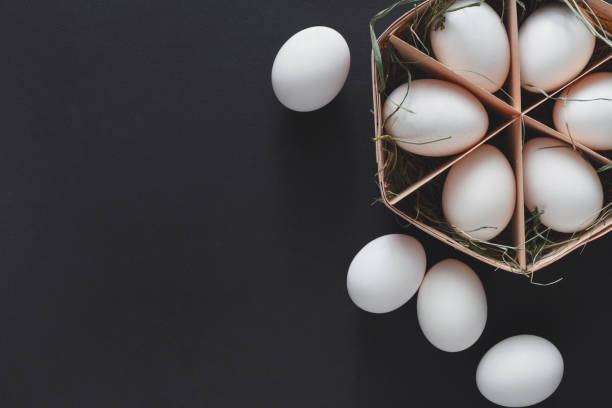 istock Fresh chicken white eggs in carton on black background 874332996