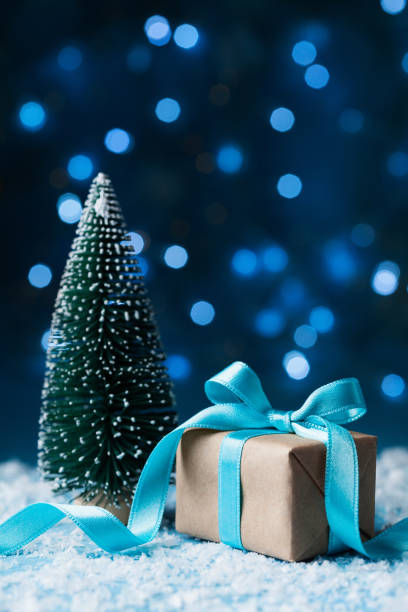 istock Christmas greeting card with bokeh effect. Fir tree and gift box on snow background. 874333304