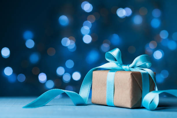 istock Christmas gift box or present with bow ribbon on magic blue bokeh background. 874333434