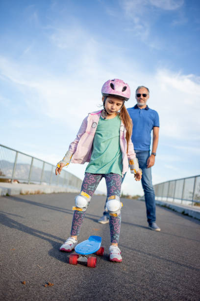 istock Worried Father Watching Daughter Riding Skateboard 874340444