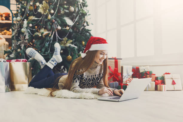 fille heureuse dans santa hat clavardant sur ordinateur portable - floor gymnastics photos et images de collection