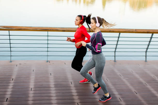 istock Two young women running by river 874347060