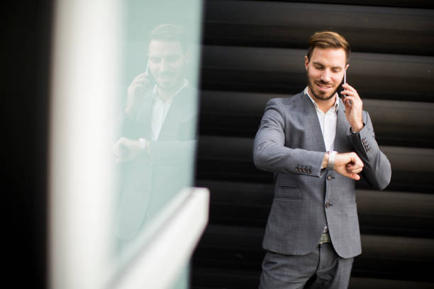 istock Businessman using mobile phone and looking on the watch 874347838