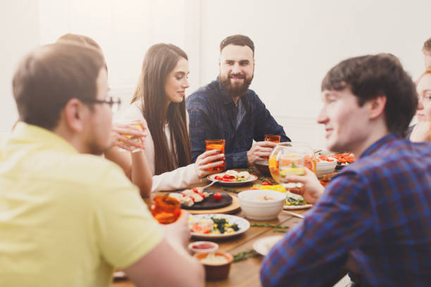 istock Group of happy people at festive table dinner party 874349332