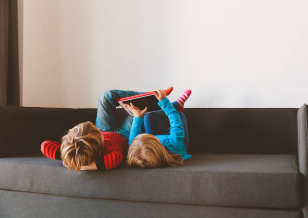 istock little boy and girl looking at touch pad at home 874367752
