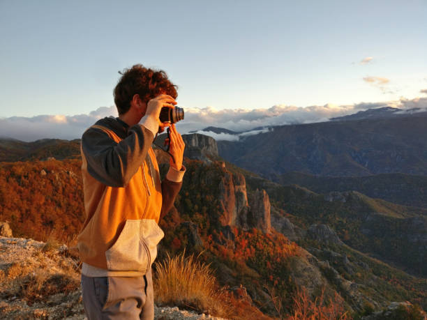 istock Man taking picture of sunset in mountains 874376454