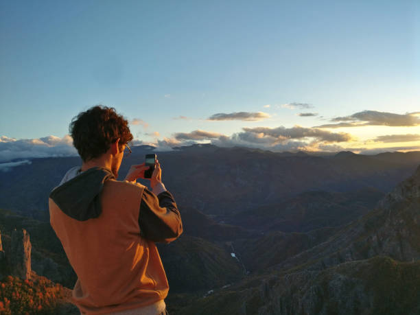 istock Man taking picture of sunset in mountains 874376692