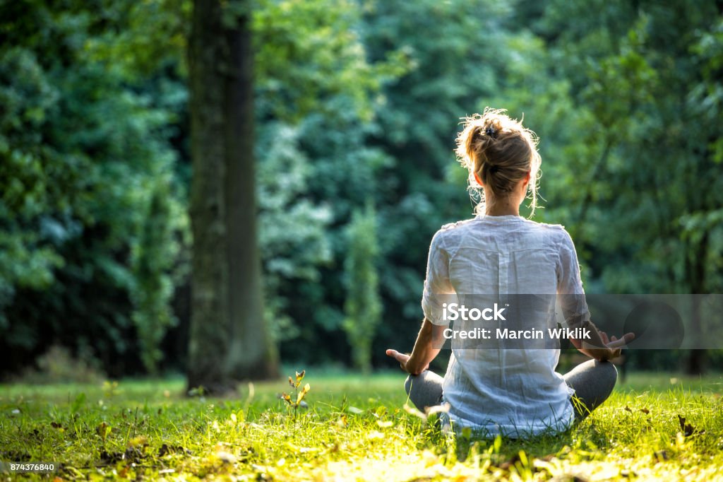 Outdoor meditation Young blonde woman meditating in the park Meditating Stock Photo