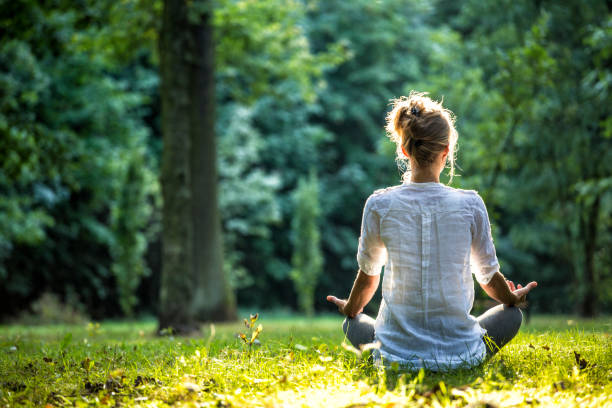 Outdoor meditation Young blonde woman meditating in the park think green stock pictures, royalty-free photos & images