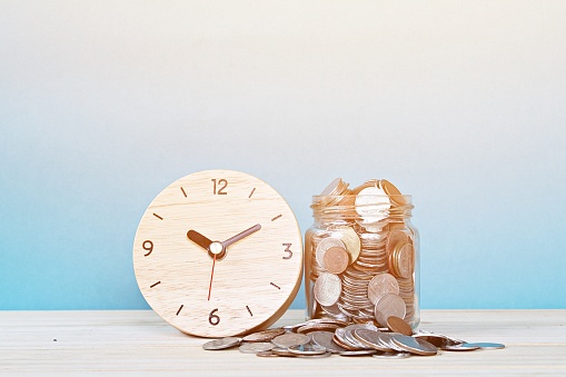 reloj despertador madera y monedas en fondo blanco photo