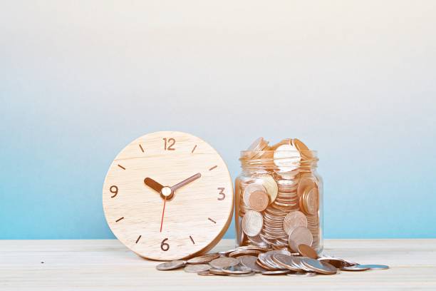 wooden alarm clock and coins on white background Business, savings time, time is money, deadline or delay concept : wooden alarm clock and coins on white background working late stock pictures, royalty-free photos & images