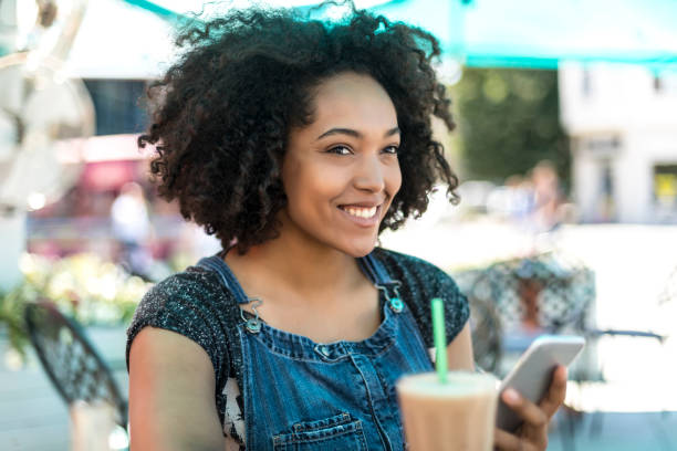 istock Smiling african woman drinking cocktail in cafeteria 874398522
