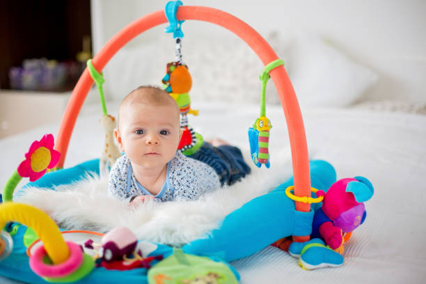 mignon petit garçon sur gym coloré, jouant avec la pendaison de jouets à la maison - club de remise en forme photos et images de collection