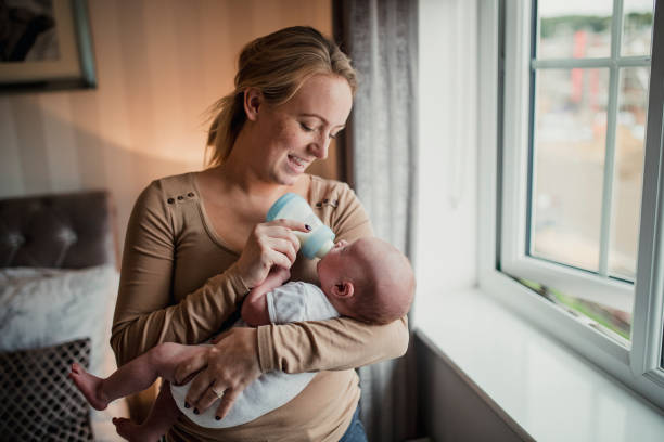 Mother Feeding Her Baby Son Mother feeding her baby son with a bottle. baby bottle stock pictures, royalty-free photos & images