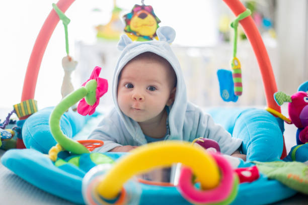 Cute baby boy on colorful gym, playing with hanging toys at home Cute baby boy on colorful gym, playing with hanging toys at home, baby activity and play center for early infant development. Kids playing at home leisure facilities stock pictures, royalty-free photos & images