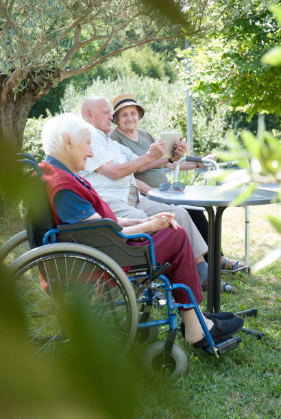 istock Seniors In The Nursing Home Enjoy The Summer Sitting Under The Tree Shadow 874413450