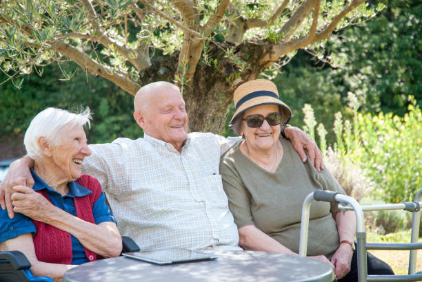 istock Seniors In The Nursing Home Enjoy The Summer Sitting Under The Tree Shadow 874413458
