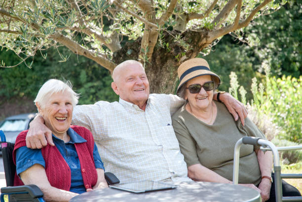 istock Seniors In The Nursing Home Enjoy The Summer Sitting Under The Tree Shadow 874413462