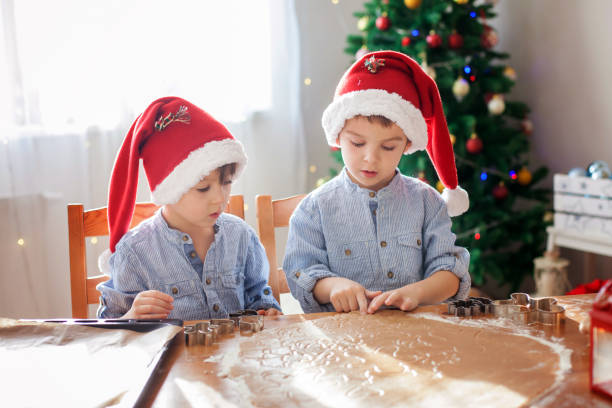 istock Two cute boys with santa hat, preparing cookies at home, Christmas tree 874418478