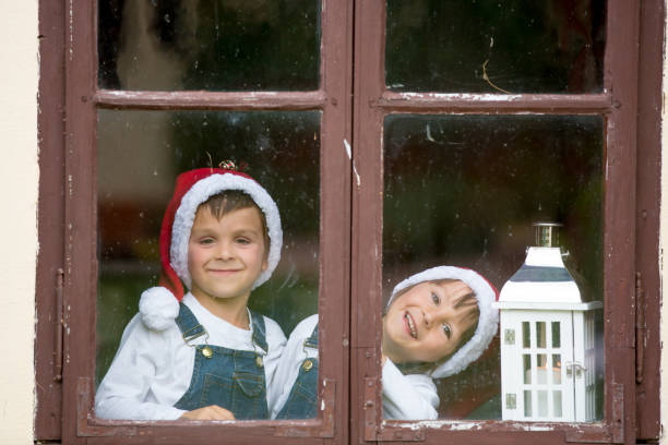 istock Two cute boys, brothers, looking through a window, waiting for Santa 874419688