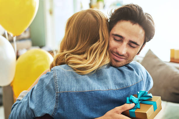 This is the best birthday ever! Shot of a cheerful young man hugging his girlfriend after receiving a gift from her at home gift for girlfriend stock pictures, royalty-free photos & images