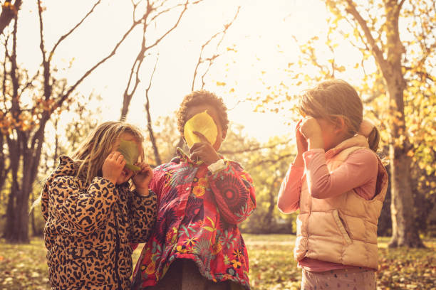 Little girls hiding behind fallen leaves.