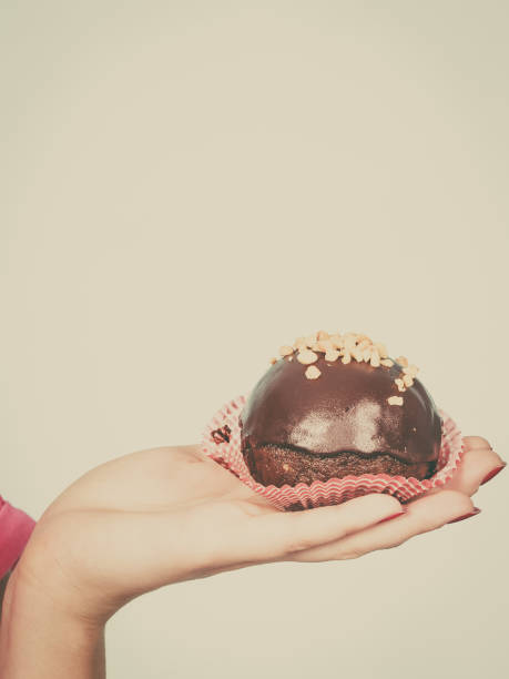 istock Woman hand holding chocolate cupcake about to bite 874426654